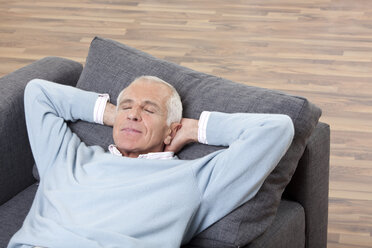 Mann mit geschlossenen Augen, auf der Couch liegend, lächelnd - CLF00912