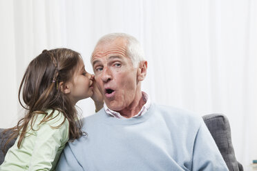 Girl (6-7) whispering into grandfather's ear, close-up - CLF00906