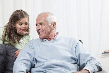 Granddaughter (6-7) with head in hand listening to grandfather - CLF00905