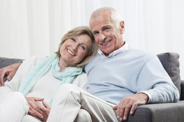 Senior couple sitting on couch, smiling, portrait - CLF00882