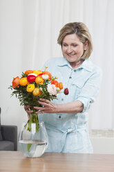Frau arrangiert Blume in Blumenvase, lächelnd, Porträt - CLF00878