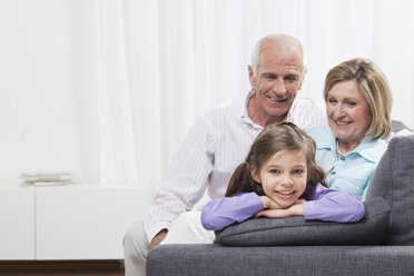 Granddaughter (6-7) with head in hand and grandparents smiling - CLF00873