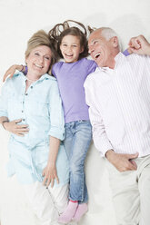 Granddaughter (6-7) lying with grandparents, smiling - CLF00870