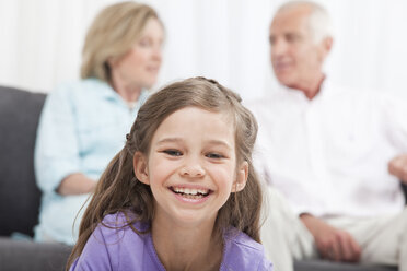 Enkelin (6-7) lächelnd mit Großeltern im Hintergrund - CLF00864