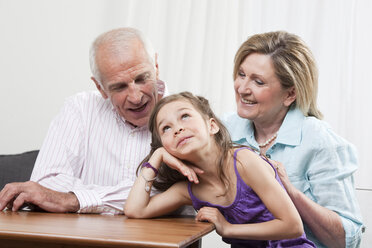 Enkelin (6-7), Kopf in der Hand mit Großeltern, lächelnd - CLF00861