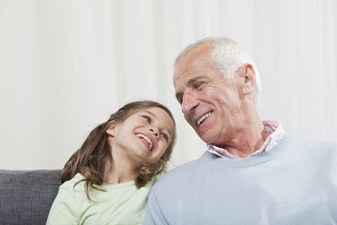 Grandfather and granddaughter (6-7) looking eachother, smiling - CLF00852