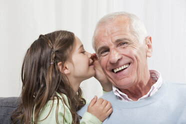 Girl (6-7) whispering into grandfather's ear, close-up - CLF00851