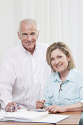 Senior couple doing paperwork, smiling, portrait - CLF00848