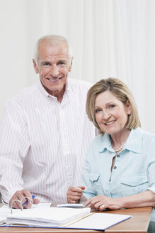 Älteres Paar erledigt Papierkram, lächelnd, Porträt - CLF00848