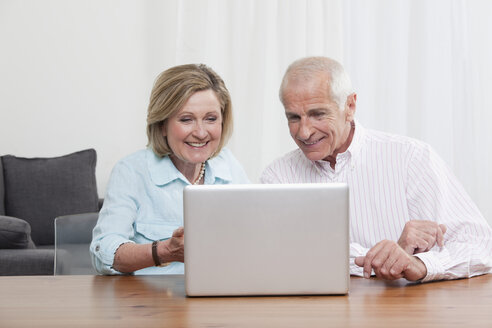 Älteres Ehepaar benutzt lächelnd einen Laptop - CLF00844