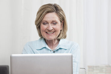 Woman using laptop, smiling - CLF00841