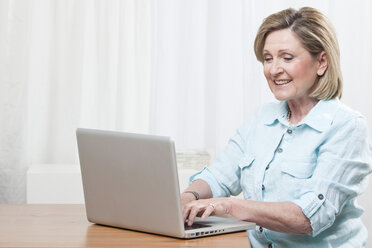 Woman using laptop, smiling - CLF00840