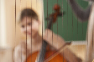 Deutschland, Emmering, Nahaufnahme einer Harfe mit junger Frau, die im Hintergrund ein Musikinstrument spielt - RNF00339