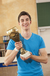 Germany, Emmering, Teenage boy holding trophy, smiling, portrait - RNF00332