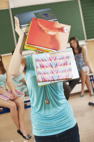 Deutschland, Emmering, Jugendliches Mädchen mit herabfallenden Büchern vom Kopf, lizenzfreies Stockfoto