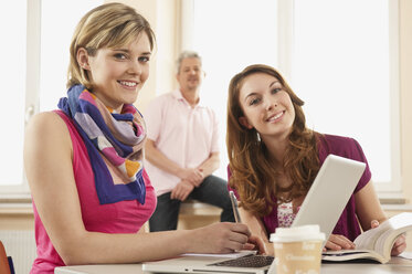 Germany, Emmering, Students with laptop and teacher in background - RNF00297