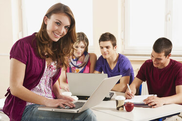 Deutschland, Emmering, Jugendliches Mädchen mit Laptop, Studenten mit Laptop im Hintergrund - RNF00291
