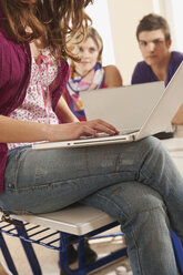 Germany, Emmering, Teenage girl using laptop with students in background - RNF00289