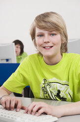 Germany, Emmering, Teenage boy (14-15) using computer with student in background - WESTF14691