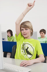 Deutschland, Emmering, Jugendlicher (14-15) mit erhobener Hand und Studenten am Computer im Hintergrund - WESTF14690
