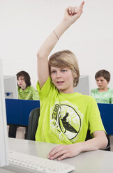 Germany, Emmering, Teenage boy (14-15) hand raised with students using computer in background - WESTF14690