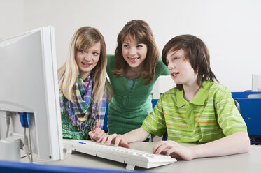 Deutschland, Emmering, Junge am Computer und Mädchen schauen zu, lächelnd - WESTF14663