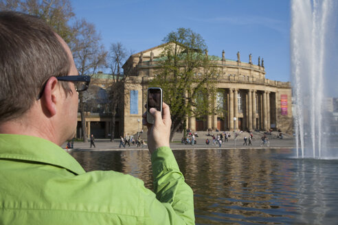 Deutschland, Stuttgart, Älterer Mann, der ein Bild des Opernhauses mit seinem Handy aufnimmt - WDF00745