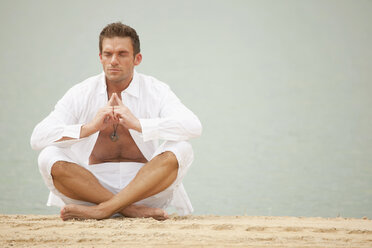 Germany, Bavaria, Man meditating with quarry pond in background - KEF00015