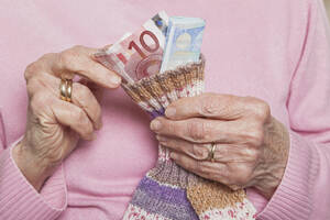 Deutschland, ältere Frau, die Geld aus einem Geldsack zählt, Mittelteil - GWF01166