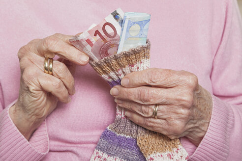 Germany, Senior woman counting money from money sock, mid section - GWF01166