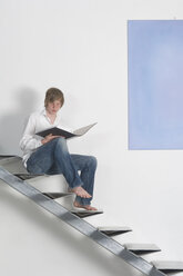 Jugendlicher mit Ordner auf der Treppe sitzend - CRF01903
