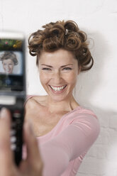 Deutschland, Frau fotografiert sich selbst mit Handy, lächelnd - WESTF14943