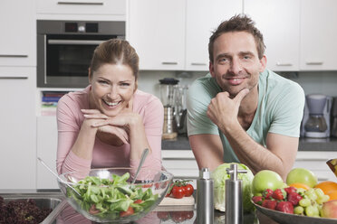 Germany, Couple with vegetables and fruits on kitchen worktop, smiling, portrait - WESTF14890