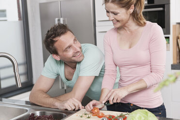 Deutschland, Ehepaar bereitet Salat in der Küche vor, lächelnd - WESTF14889