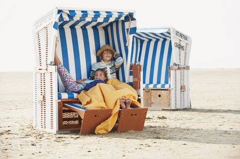 Deutschland, St.Peter-Ording, Nordsee, Kinder (6-9) ruhen sich in einem Strandkorb mit Kapuze aus - WESTF15069