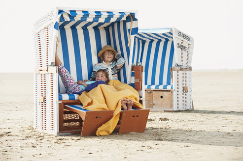 Germany, St.Peter-Ording, North Sea, Children (6-9) resting on hooded beach chair - WESTF15069