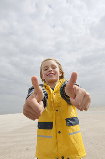 Deutschland, St.Peter-Ording, Nordsee, Junge (8-9) in Regenjacke zeigt Daumen hoch Zeichen am Strand - WESTF15059