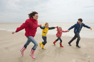Germany, St. Peter-Ording, North Sea, Family holding hands and running on beach - WESTF15056