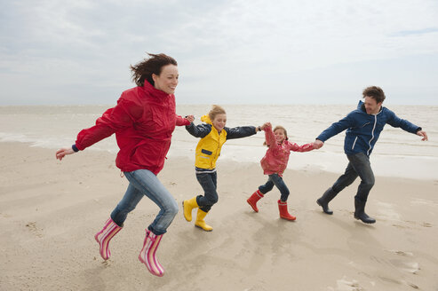 Deutschland, St. Peter-Ording, Nordsee, Familie hält sich an den Händen und läuft am Strand - WESTF15056