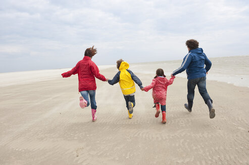 Deutschland, St. Peter-Ording, Nordsee, Familie hält sich an den Händen und läuft am Strand - WESTF15053