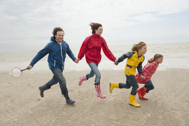 Germany, St. Peter-Ording, North Sea, Family holding hands and running on beach - WESTF15052