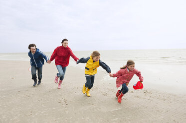 Deutschland, St. Peter-Ording, Nordsee, Familie hält sich an den Händen und läuft am Strand - WESTF15051