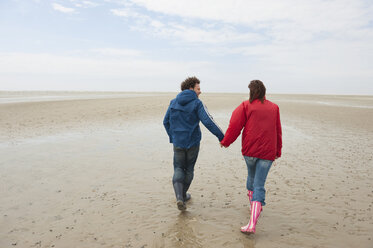 Germany, St. Peter-Ording, North Sea, Couple holding hands and walking on beach - WESTF15044