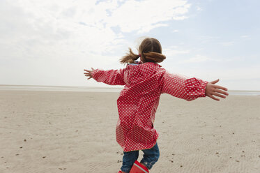 Deutschland, Nordsee, St.Peter-Ording, Mädchen (6-7) in Regenjacke spielt am Strand, Rückansicht - WESTF15037