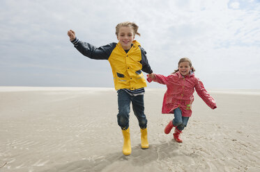 Deutschland, St. Peter-Ording, Nordsee, Kinder (6-9) halten sich an den Händen und laufen am Strand - WESTF15033