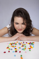 Young woman looking at candies, smiling - SKF00238