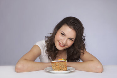 Junge Frau sitzt mit einem Teller Kuchen, lächelnd, Porträt - SKF00236