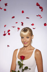 Young woman with red rose against gray background, portrait, smiling - SKF00173