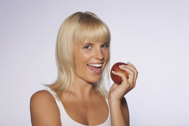 Porträt einer jungen Frau mit einem Apfel in der Hand, lächelnd - SKF00157