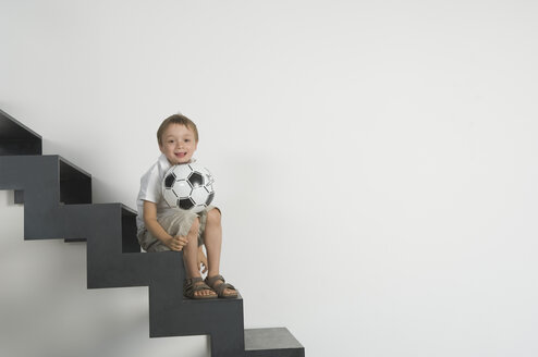 Germany, Boy (4-5 years) sitting on stairs with football - CRF001918